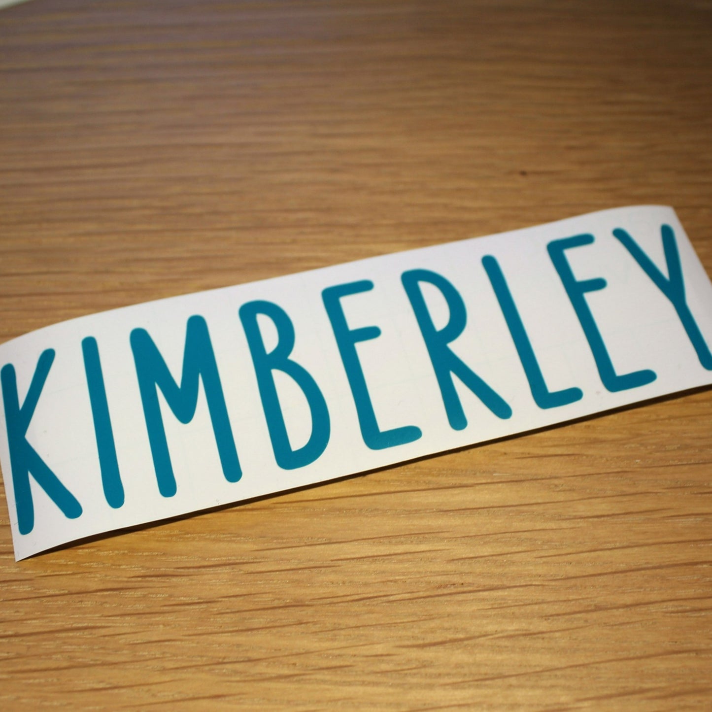 Name in plain capitals. Teal lettering.