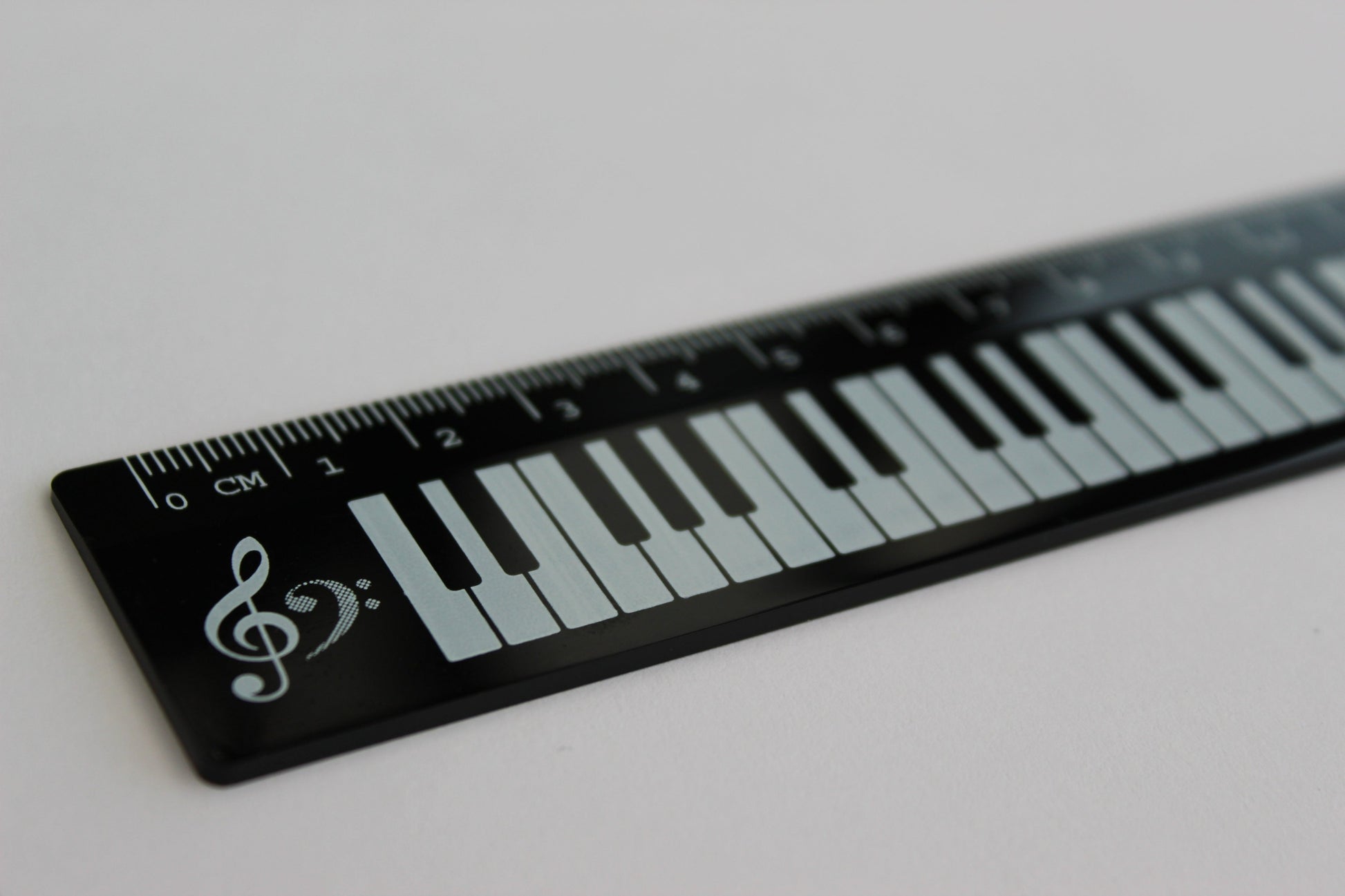 Black ruler with a piano keyboard and treble and bass clef design.
