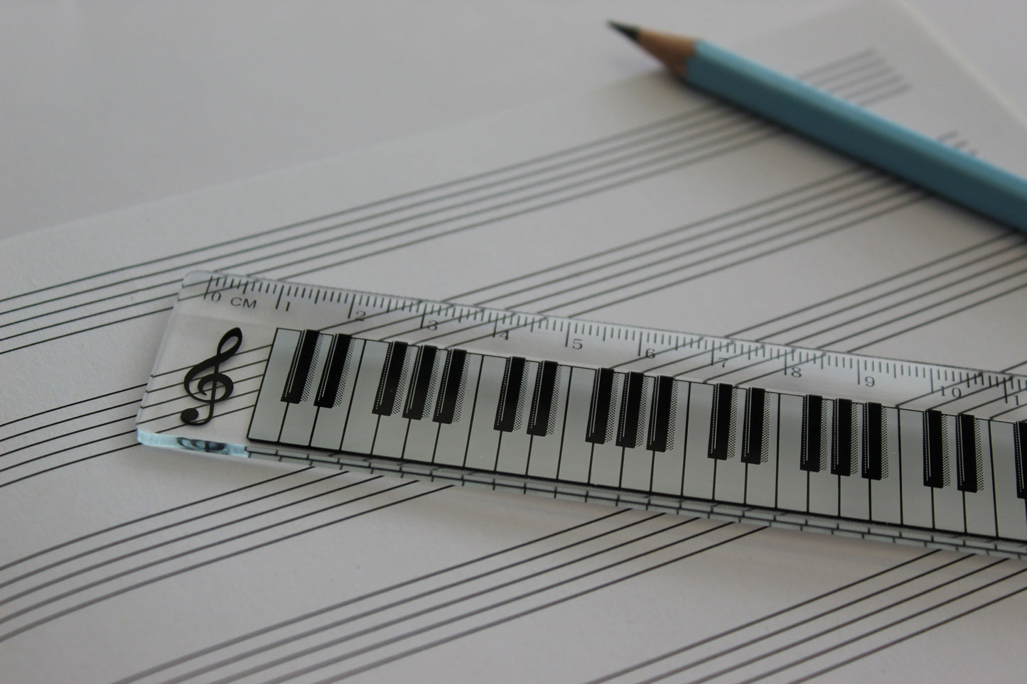 Clear ruler with a piano keyboard. Manuscript paper and a pencil in the background.