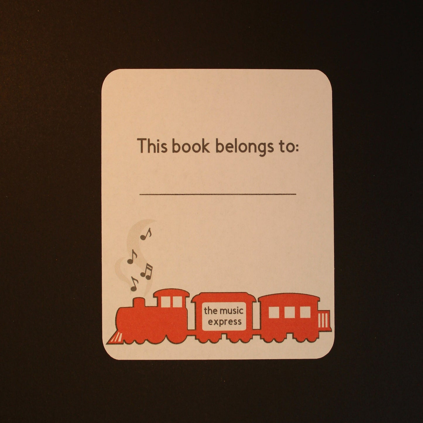 White bookplate with a red steam train and music notes coming out of the funnel. Text reads 'this book belongs to'