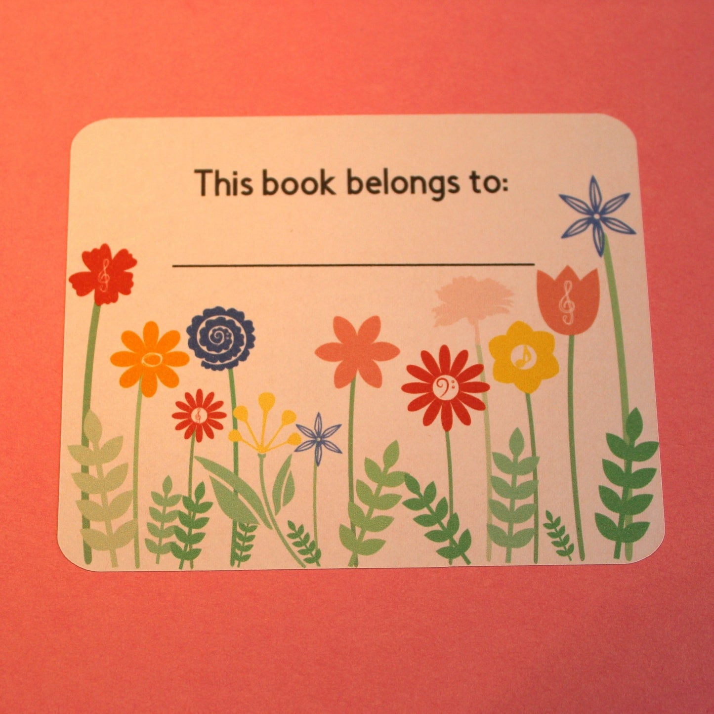 White bookplate with a colourful floral design. Displays the words 'this book belongs to'
