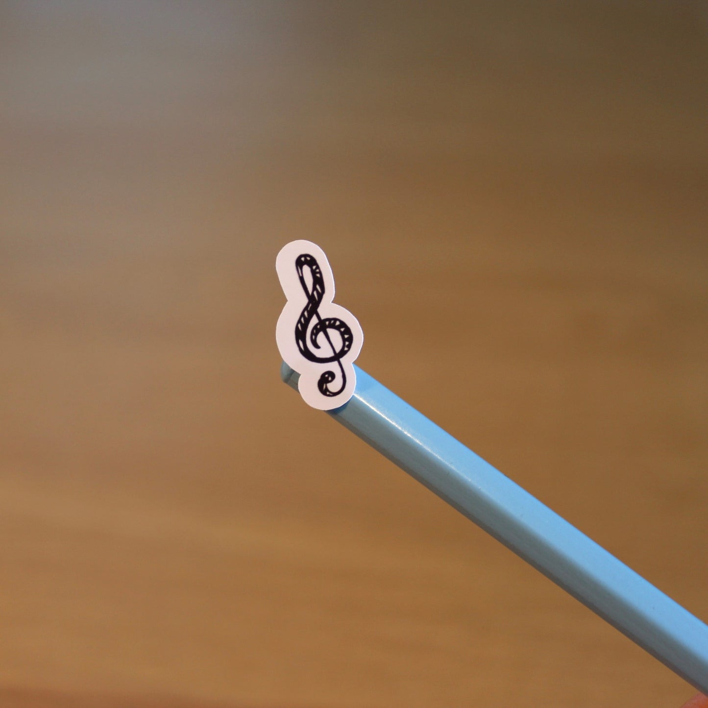 Treble clef symbol sticker displayed on the end of a pencil