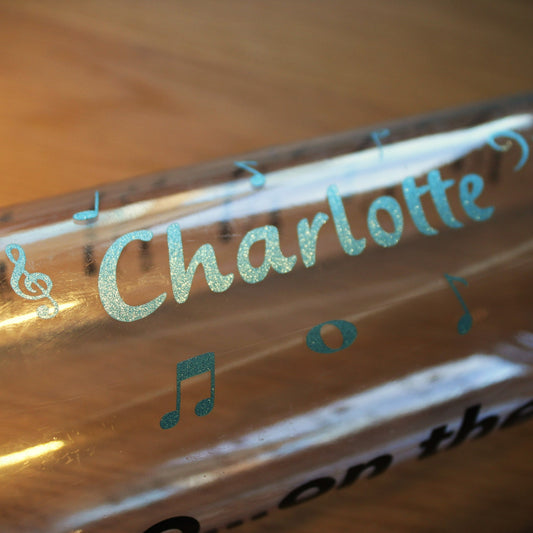 Water bottle with a name and music symbols in blue shimmer.