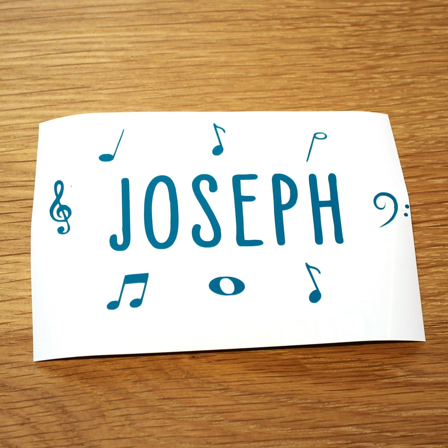 Name in plain capitals with music symbols around. Teal lettering.