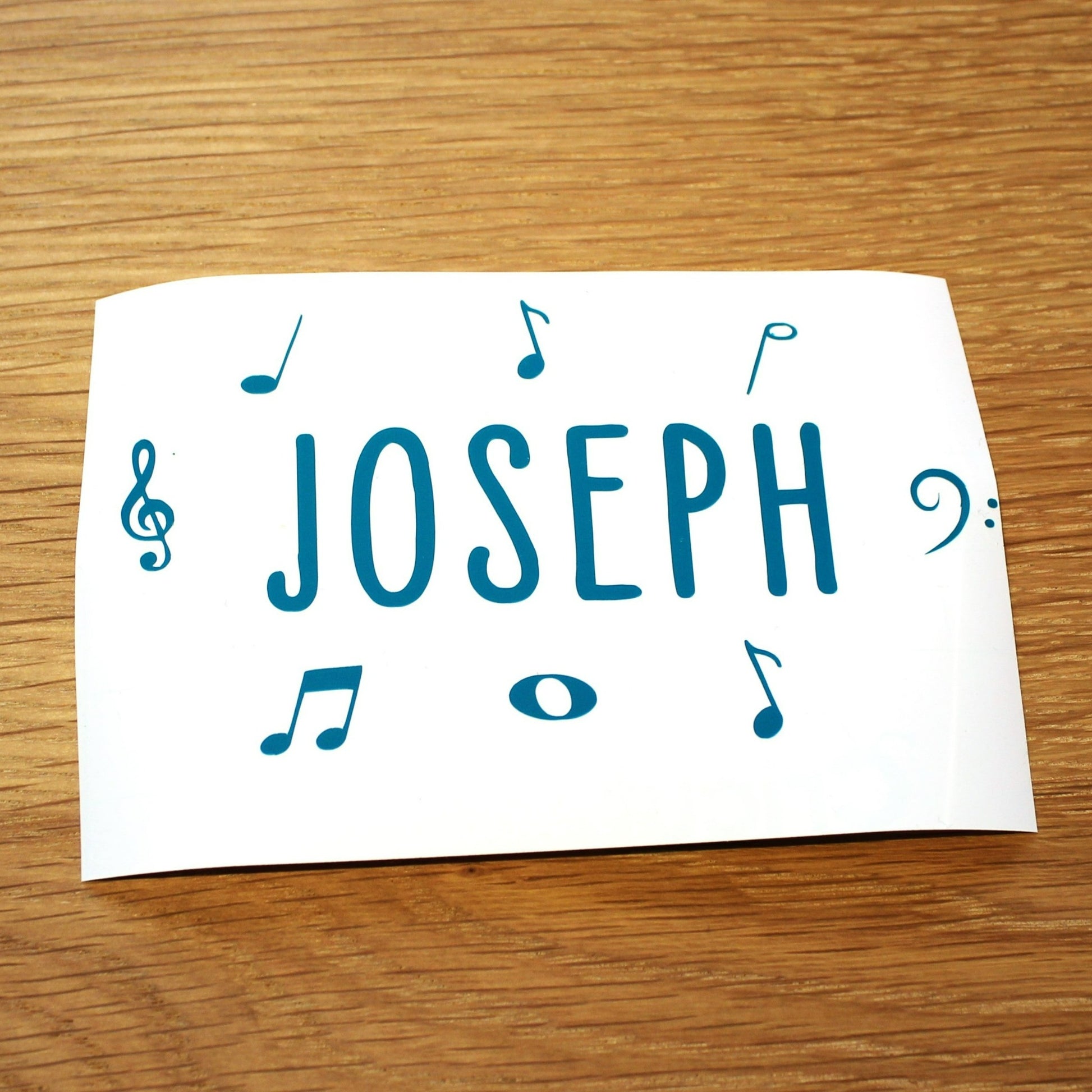 Name in plain capitals with music symbols around. Teal lettering.